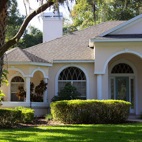 Singlestory suburban home with arched front windows a covered porch and neatly trimmed hedges in the yard Single-story suburban home with arched front windows, a covered porch, and neatly trimmed hedges in the yard