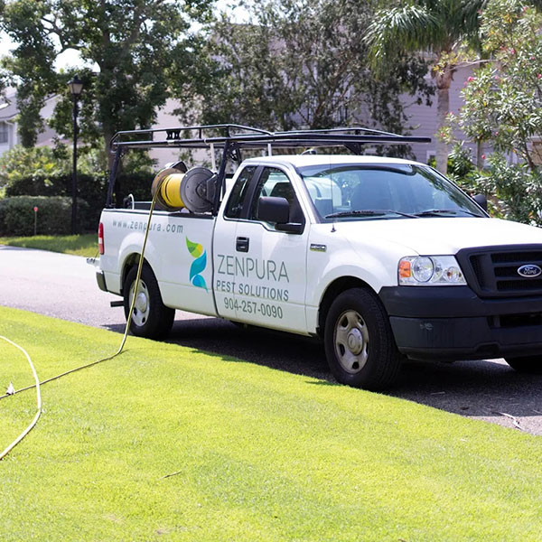 White pestcontrol van with Zenpura Pest Solutions logo parked on a sunny suburban street a yellow hose reel sits in the truck bed White pest-control van with Zenpura Pest Solutions logo parked on a sunny suburban street; a yellow hose reel sits in the truck bed.